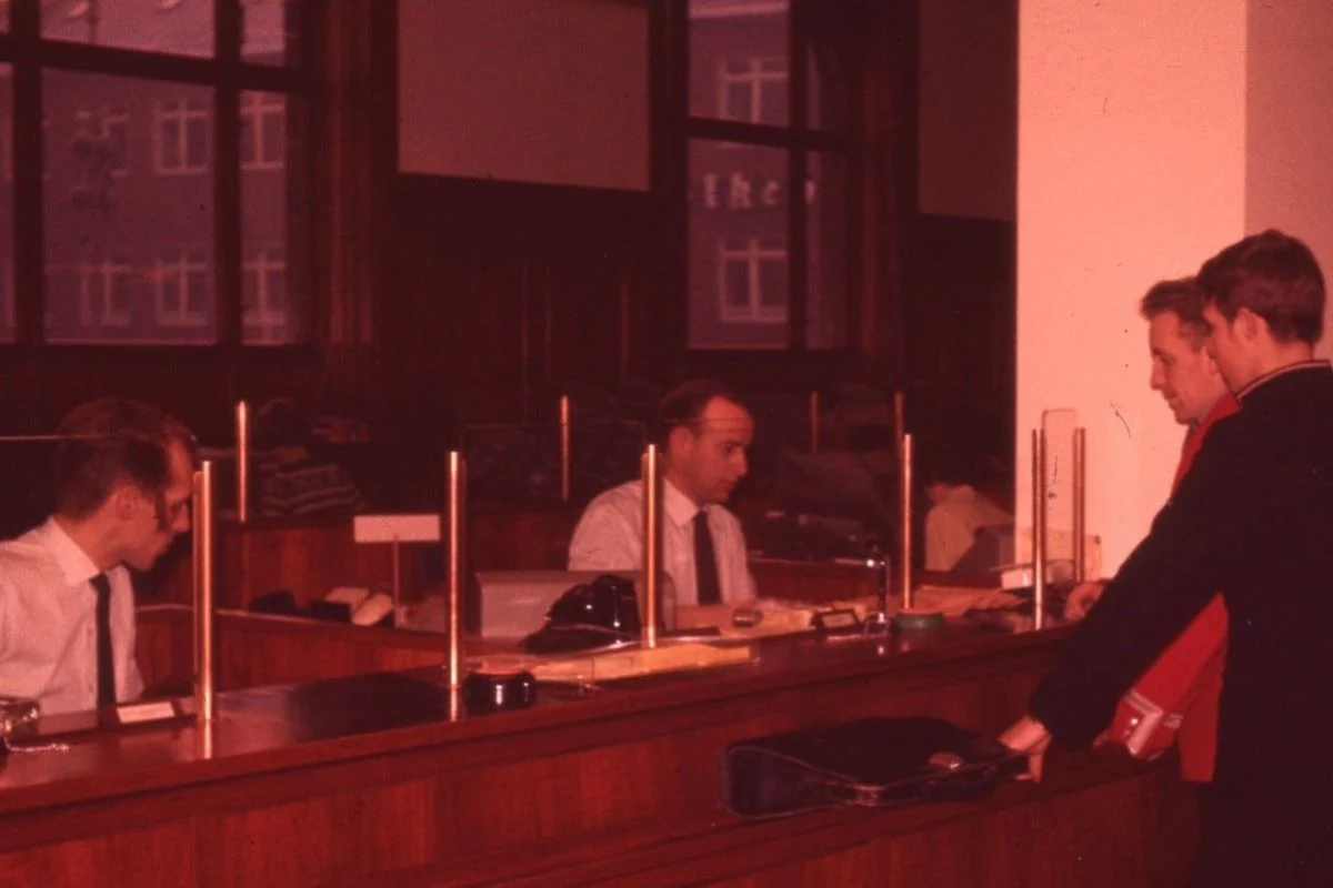 <b>Sydjylland 1955: Kasseekspedition i den moderne bank.</b> To herrer betjenes i Vejle Bank på Kirketorvet i Vejle. Banken blev ombygget i 1952 (Foto: Vejle Stadsarkiv)