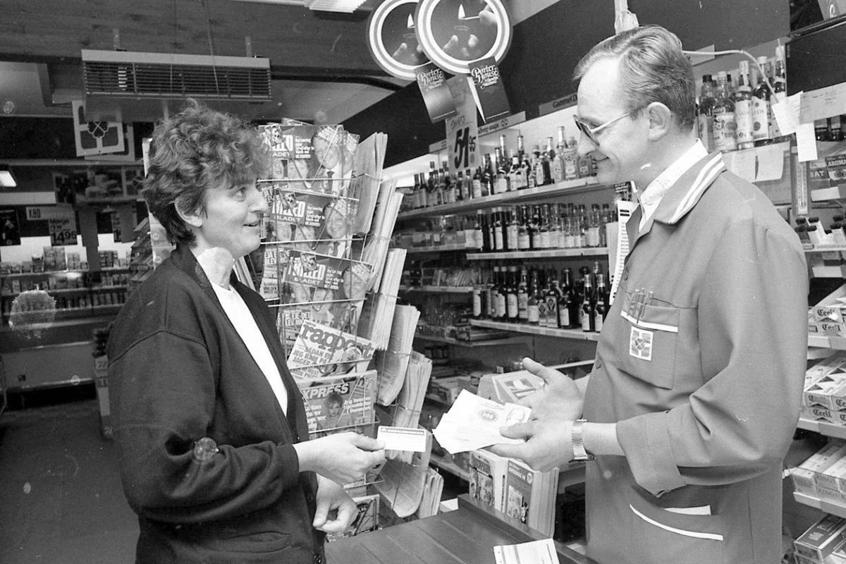 <b>Sjælland 1985: Den venlige købmand låner penge ud.</b> <i>Fattigfirserne</i> var en hård tid i mange danske husholdninger. Lille købmand i Nødebo nær Hillerød udlåner penge til en af sine trofaste, men trængende kunder. (Foto: Lokalarkivet Alsønderup-Tjæreby)