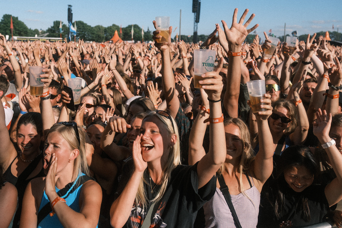Glade unge mennesker med hver deres fadøl til en 50'er. Roskilde Festival løber i år af stablen 29. juni til 6. juli 2024 (Foto: Flemming Bo Jensen/Roskilde Festival)