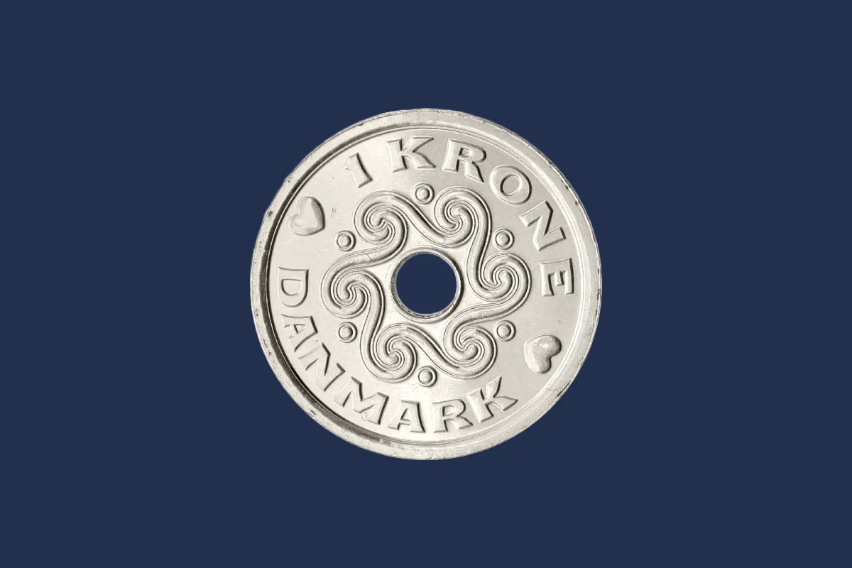 Enkronen er den mindste gyldige sølvfarvede mønt i Kongeriget Danmark. Mønten er fremstillet i kobbernikkel, har en diameter på 20,25 mm, tykkelse på 1,6 mm, vejer 3,6 g og har en riflet rand. Den første enkrone blev introduceret for danskerne i 1875 og havde et portræt af Kong Christian IX og hjertemøntmærket på forsiden. På bagsiden sås det lille rigsvåben omgivet af en delfin og et bygaks. I alt blev der præget 6,2 millioner mønter. (Foto: Danmarks Nationalbank og Oldmoney)