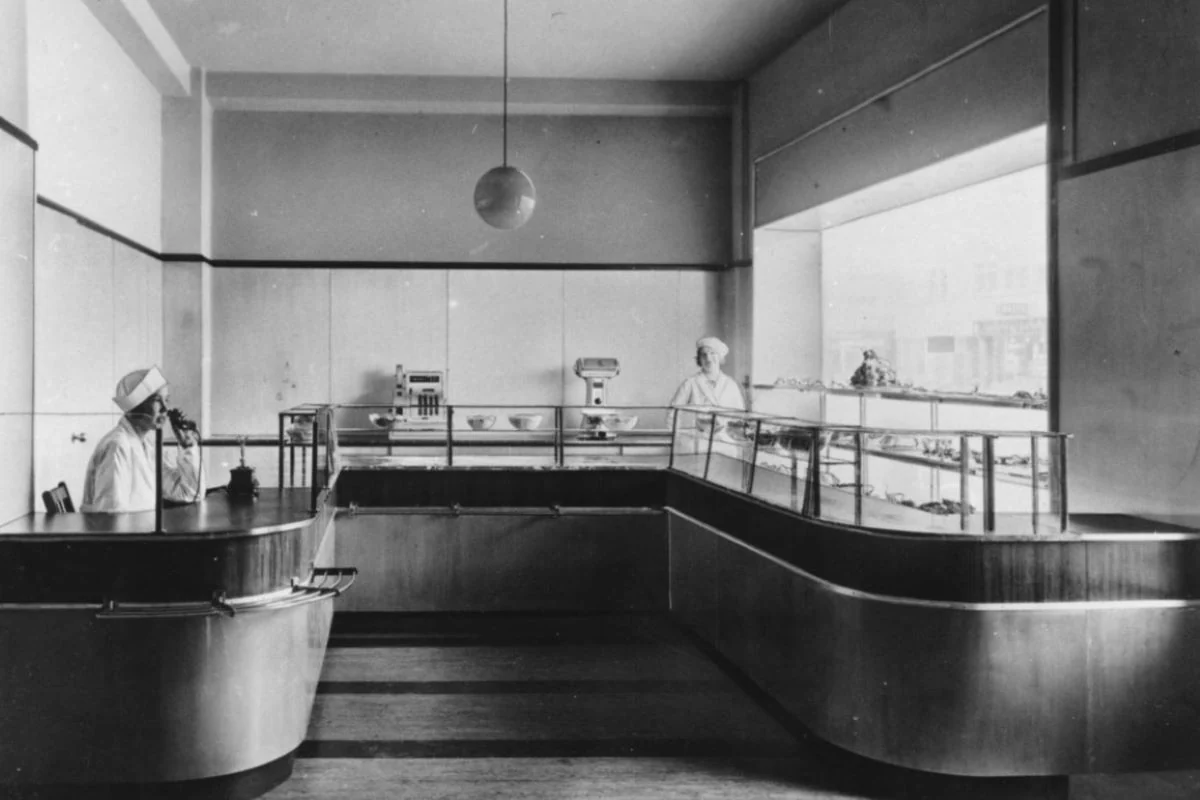 <b>Nordjylland 1935: Den moderne smørrebrødsbutik.</b> Dansk arkitektur og design fornyer sig hastigt i disse år - funktionalismens frembrud. Nu skal vi til Aalborg, hvor smørrebrødsforretningen Scala på Vesterbro 76 i 1935 slår dørene op i opsigtsvækkende funkisstil. (Foto: Aalborg Stadsarkiv)