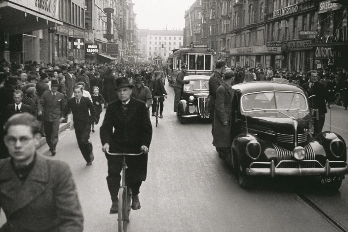 <b>København 1942: Nazisterne fester i Danmark.</b> Trængsel på Vesterbrogade, hvor biler med bl.a. soldater fra Frikorps Danmark står som bodyguards på vognenes trinbræt, på vej fra KB-Hallen efter DNSAP's forårsappel d. 26. april 1942. (Foto: Nationalmuseet)