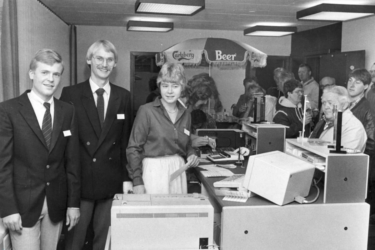 <b>Vestegnen 1983: Filialåbning i Hedehusene.</b> Bankfuldmægtige Thorkild Aas, Thomas Bolvig og Inge Nielsen byder kunderne velkommen til den nye filial af Roskilde Bank (Foto: Byhistorisk Samling og Arkiv i Høje-Taastrup Kommune)