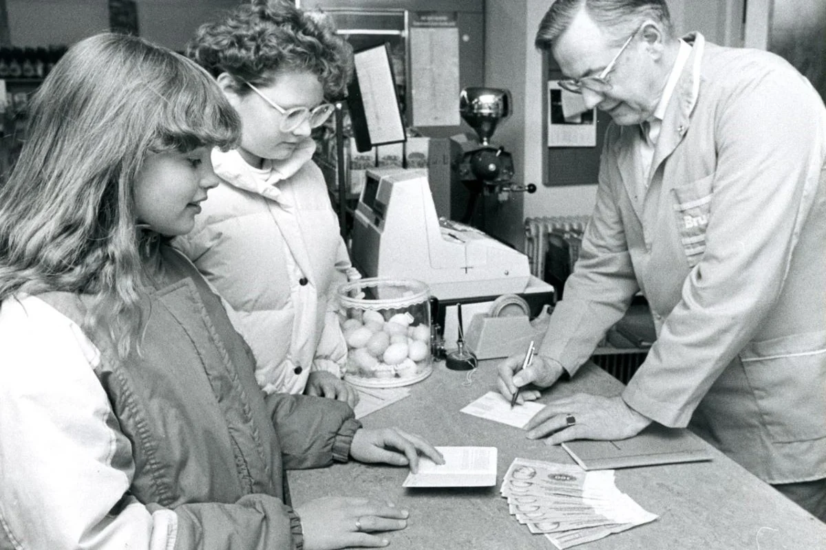 <b>Viborgegnen 1987: Landsbyens brugs blev mini-bank.</b> Randi Pedersen (forrest) og Mette Mulvad er blandt de store børn i Lånum, som ofte kommer for enten at sætte penge ind eller for at hæve dem. Uddeler Holger Sørensen må højst udlevere 1.000 kr. pr. kunde fra sin Mini-Bank i Lånum Brugsforening. (Foto: Fjandbo Arkiv)